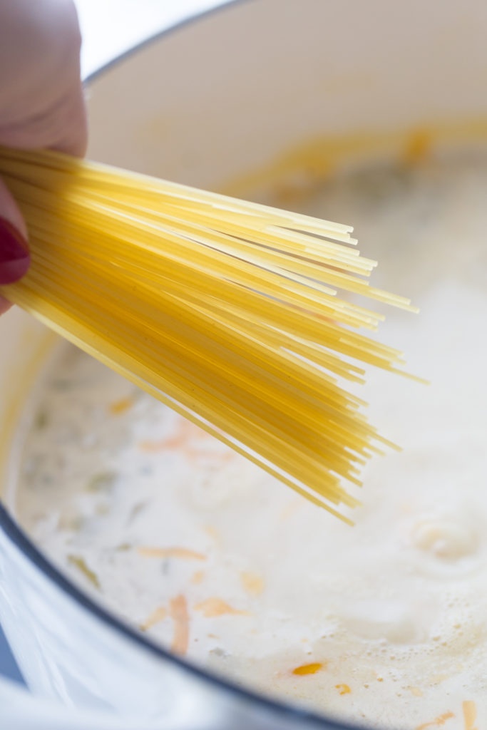 adding pasta to soup pot
