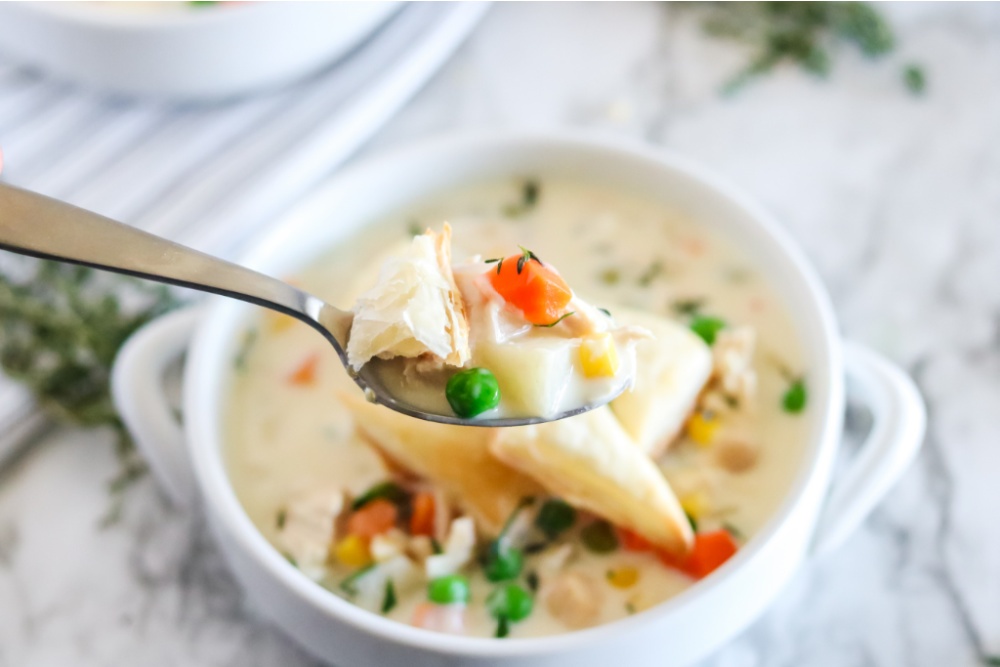 Crockpot Chicken Pie Soup in a white bowl with a spoon scooping up a bit
