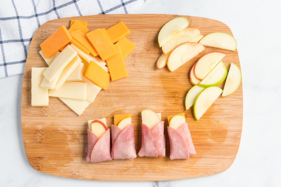Ham, cheese and apple wraps on a cutting board