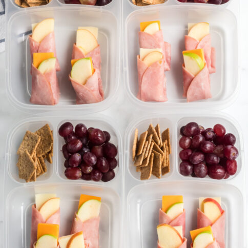 4 lunch boxes with ham, apple and cheese wraps