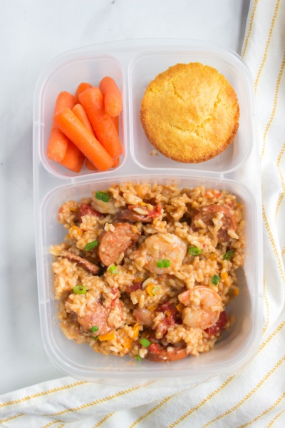 Jambalaya packed in a lunch box with muffin and baby carrots