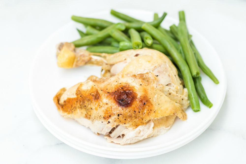 Instant Pot Dill Pickle Chicken - Chicken portion served on a white plate with green beans