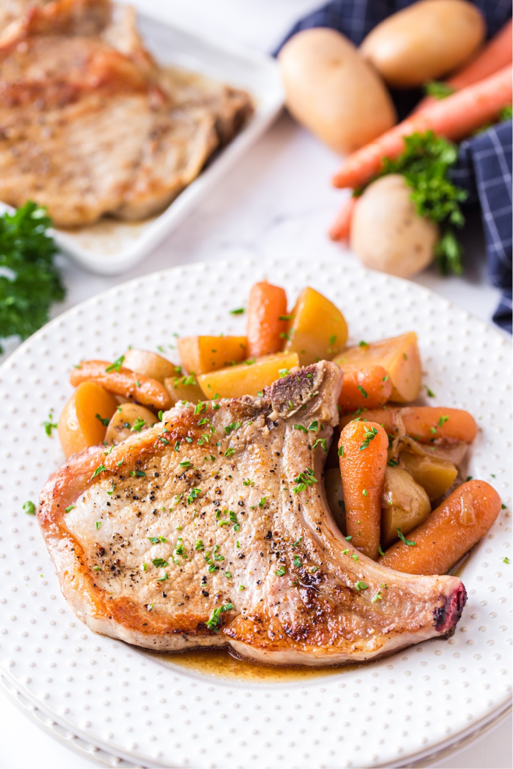 Instant pot pork chops with potatoes and carrots, served on a white plate