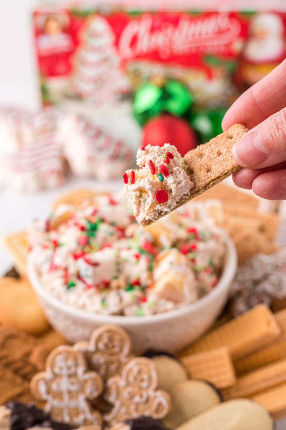 Scooping out some Little Debbie's Christmas Tree Cake Dip with a cookie