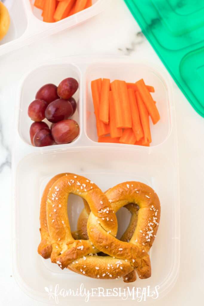 soft pretzels, grapes and carrots packed in a lunch box