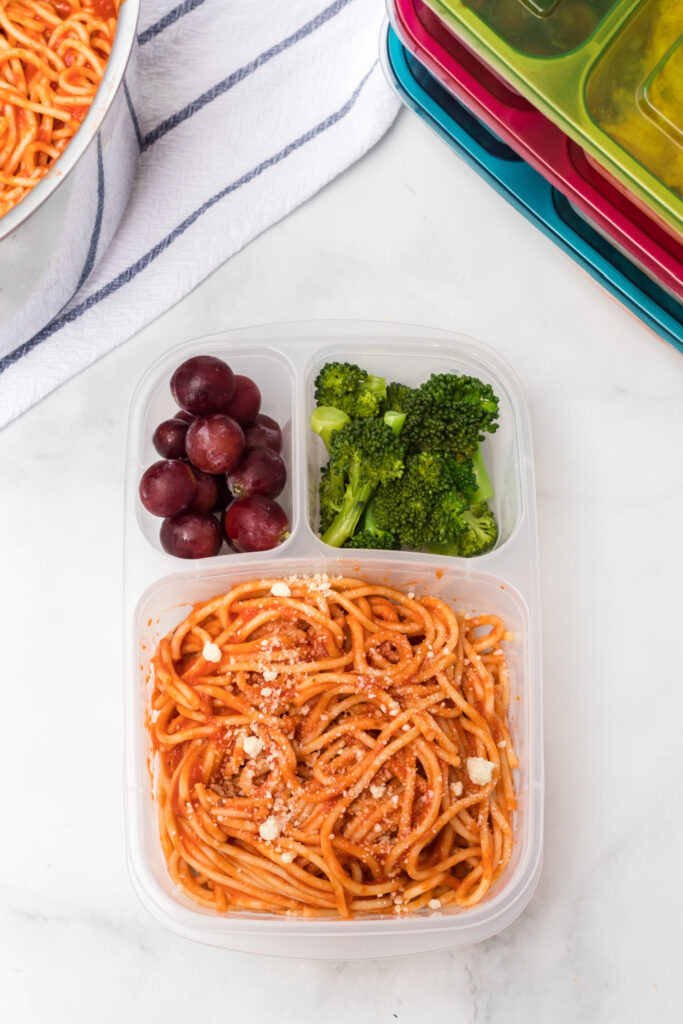 Spaghetti packed in a lunch box with grapes and broccoli