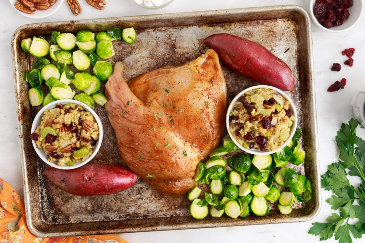 turkey breast, potato stuffing cups, and brussels sprouts on a baking sheet