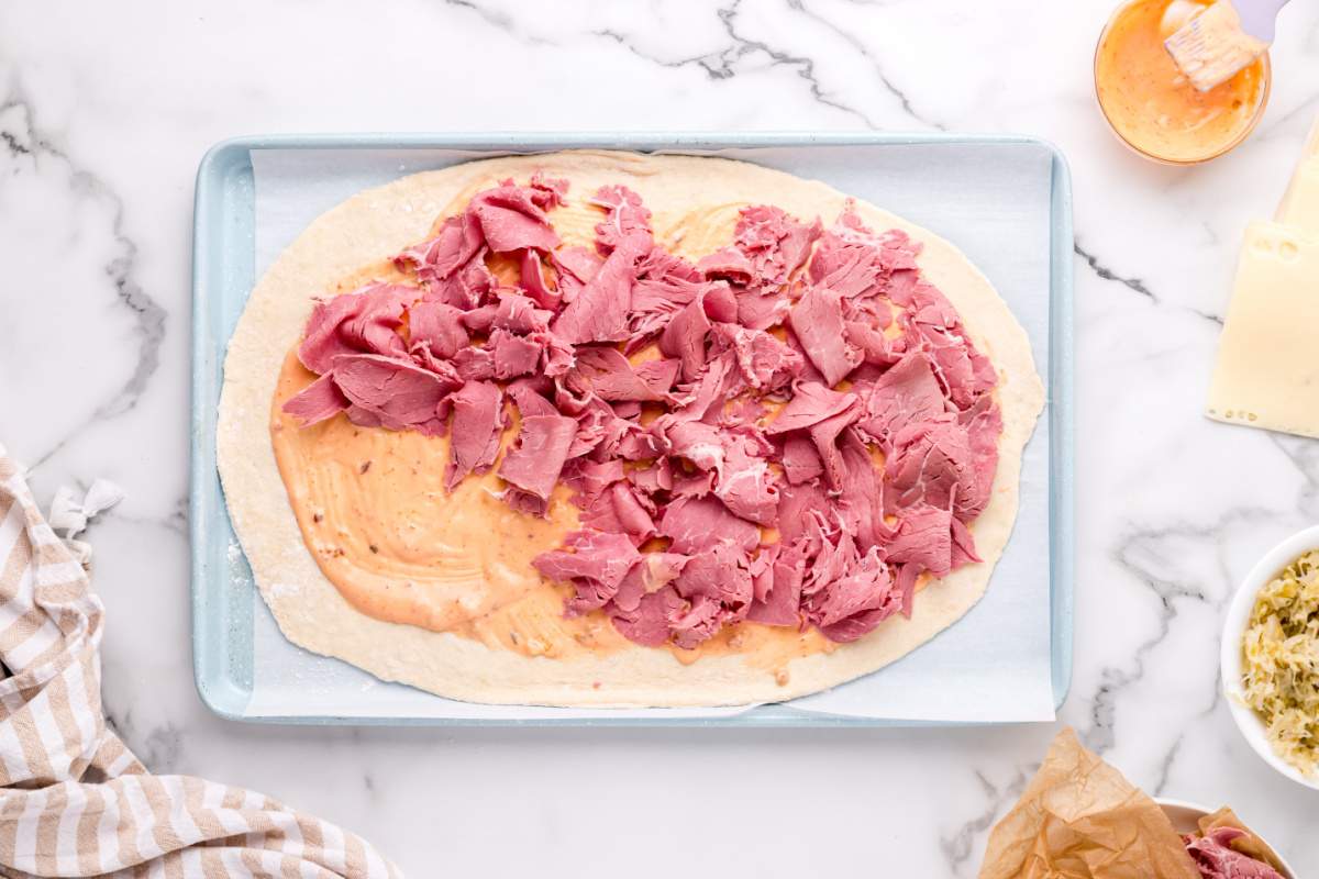 adding topping and corned beef to pizza dough