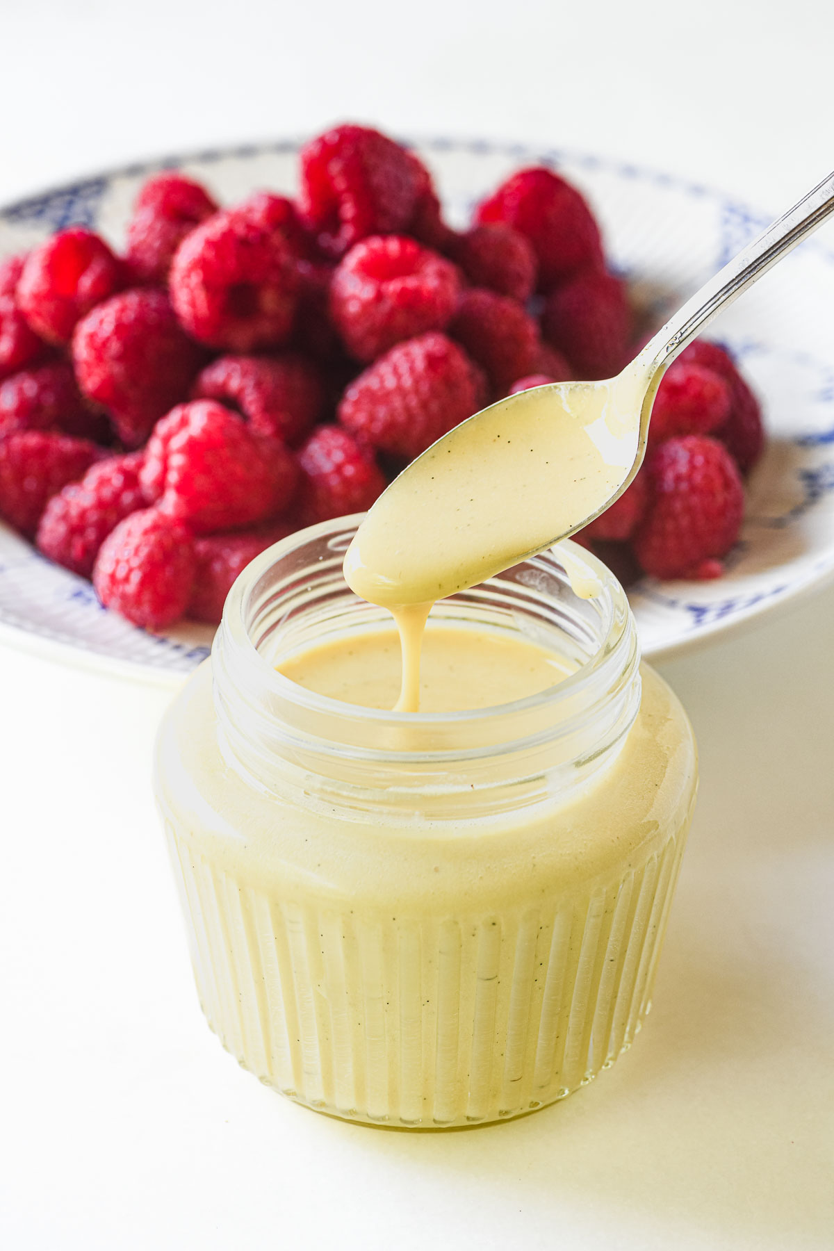 Scoop out a spoonful of heavy crème anglaise from a jar.