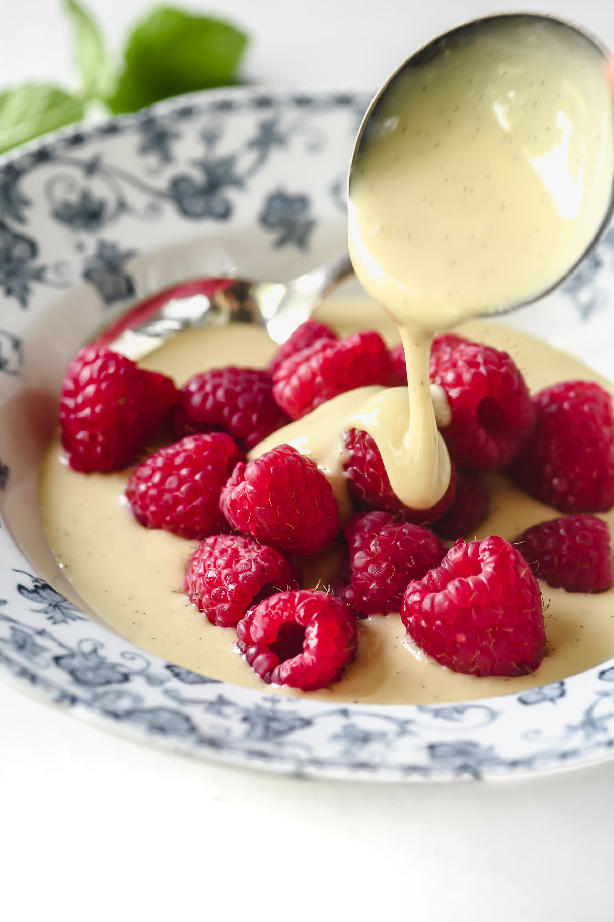 spooning crème anglaise over raspberries.