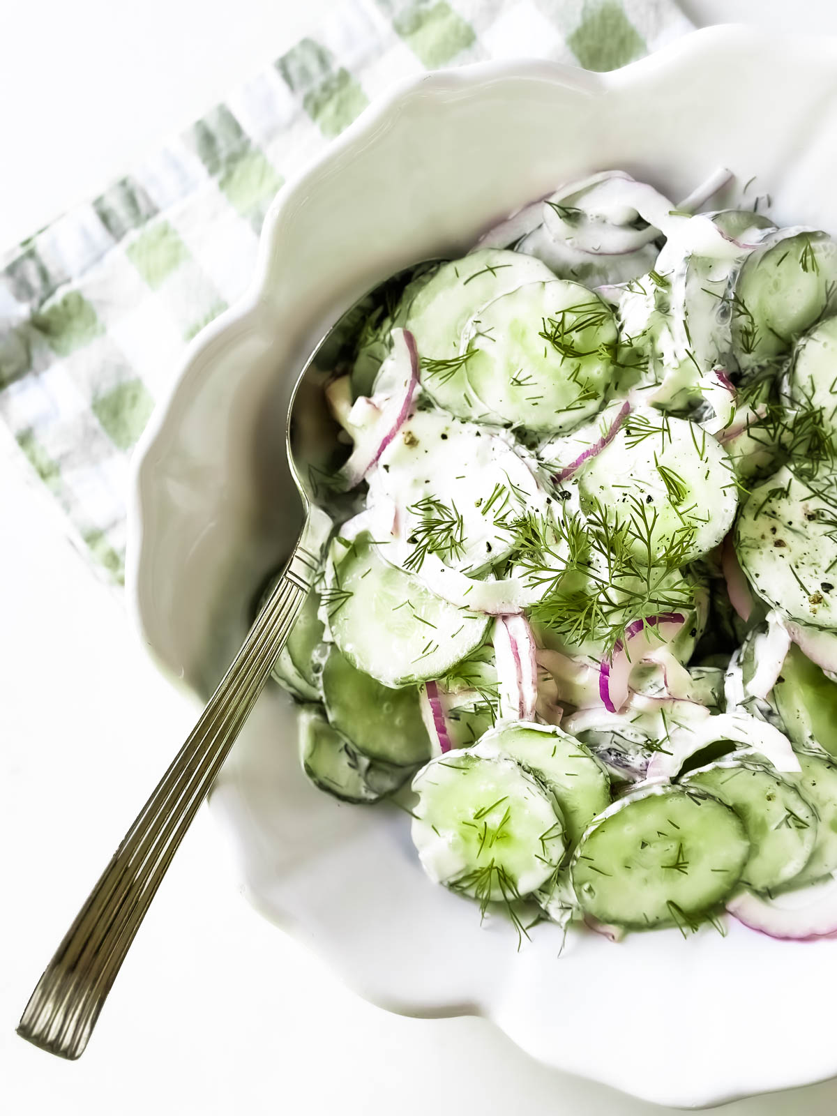 Cucumber salad with red onion and dill in a white bowl.