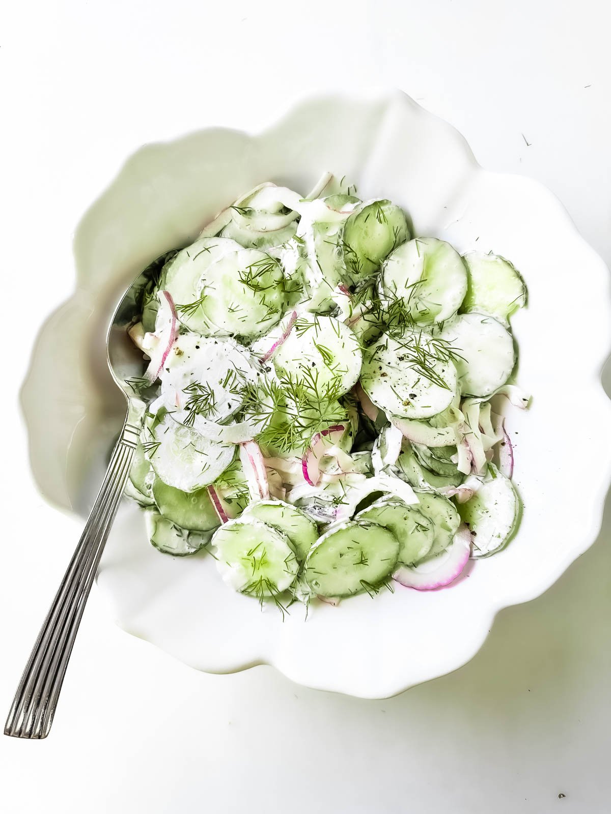 Creamy cucumber salad garnished with sour cream and dill.