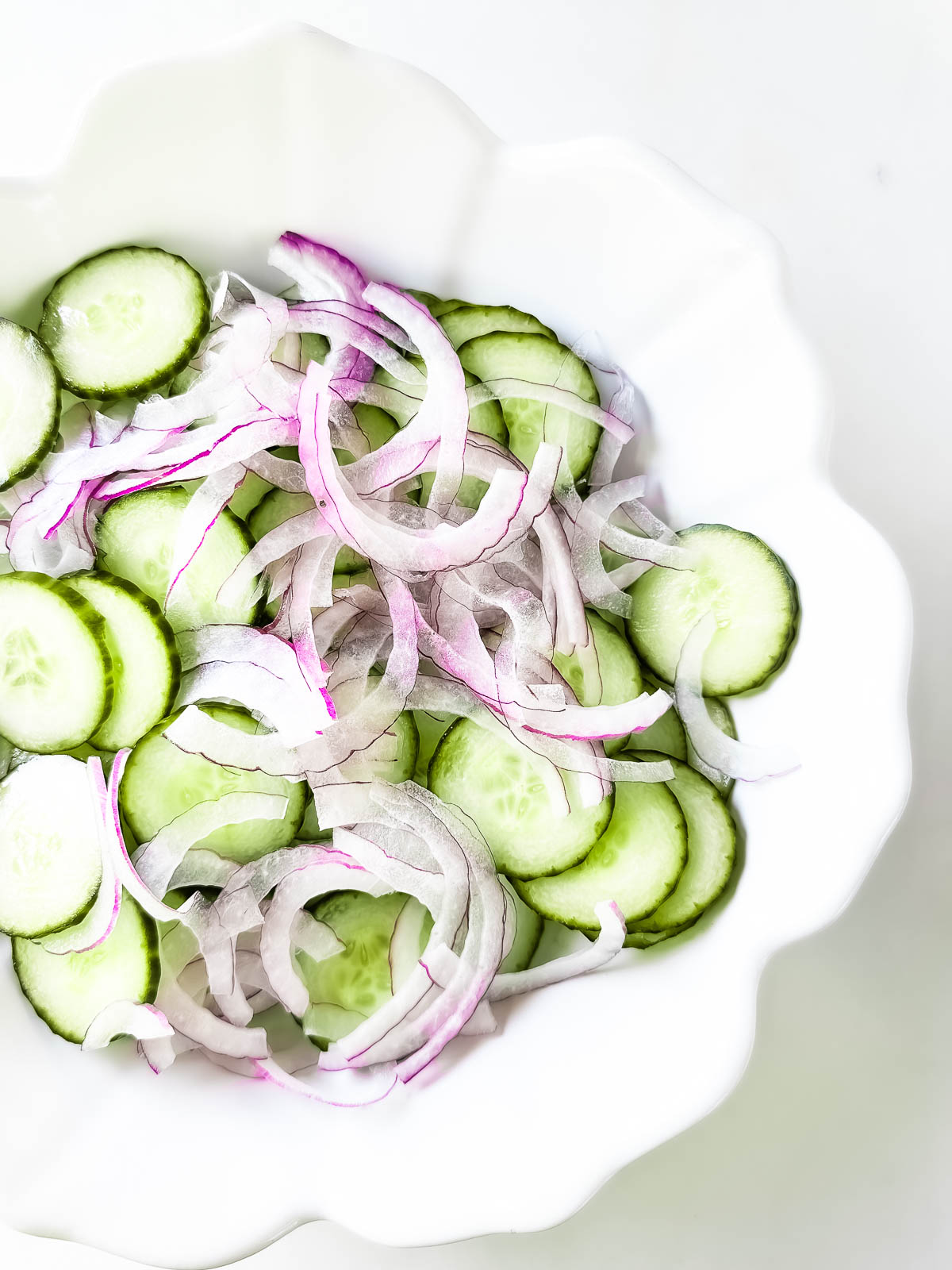 Sliced ​​cucumbers and red onions in a bowl.