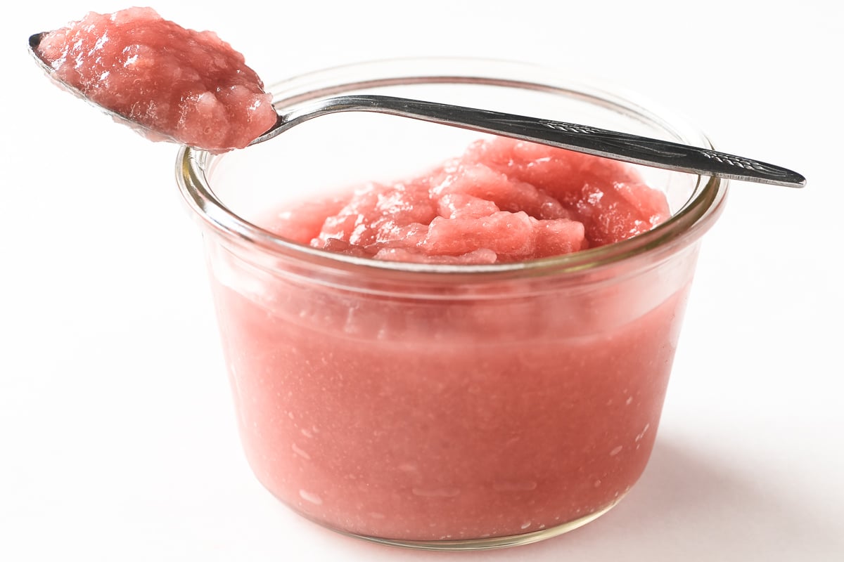 A jar of homemade rhubarb applesauce with a spoon.