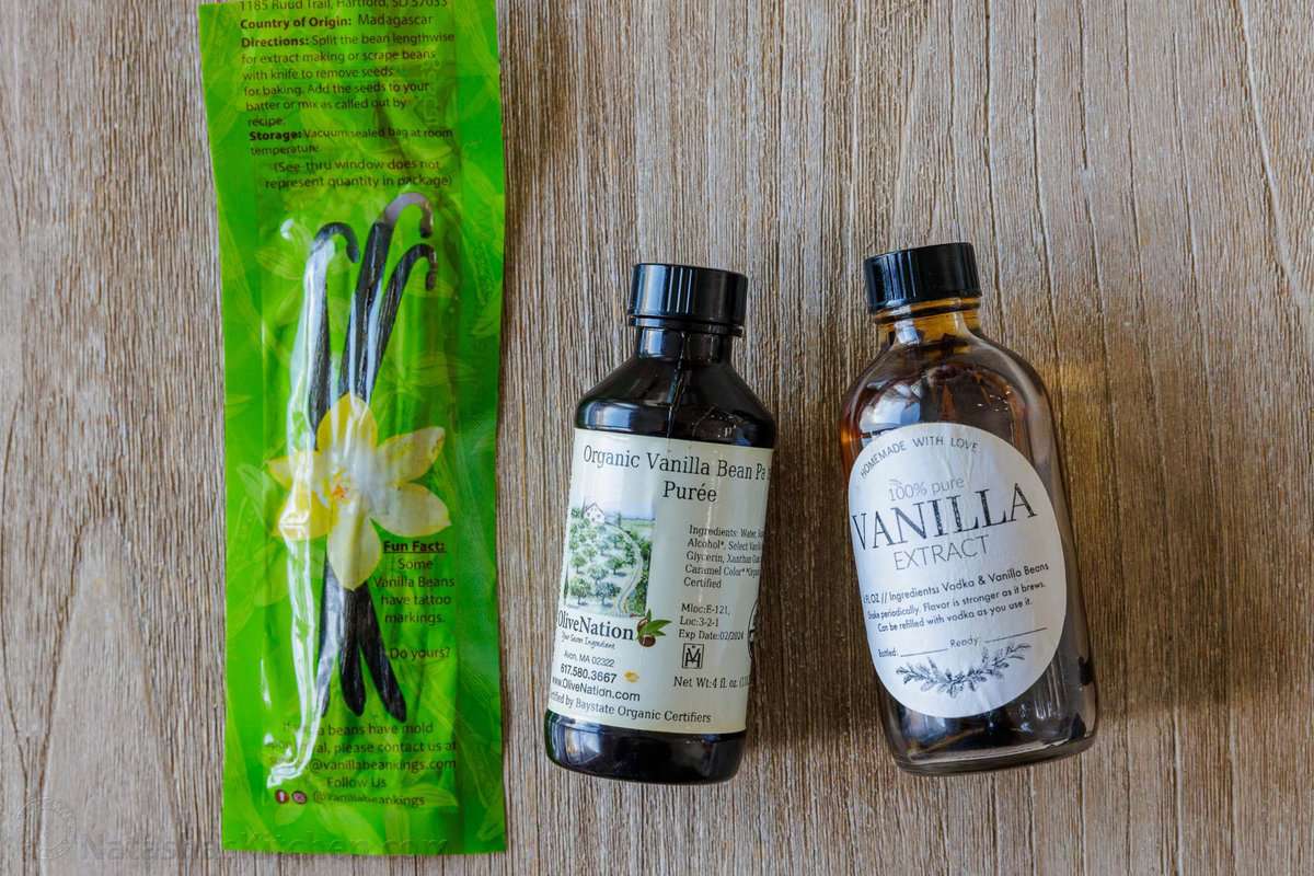 Overhead view of a package of vanilla beans pods next to bottles of vanilla bean paste and pure vanilla extract.