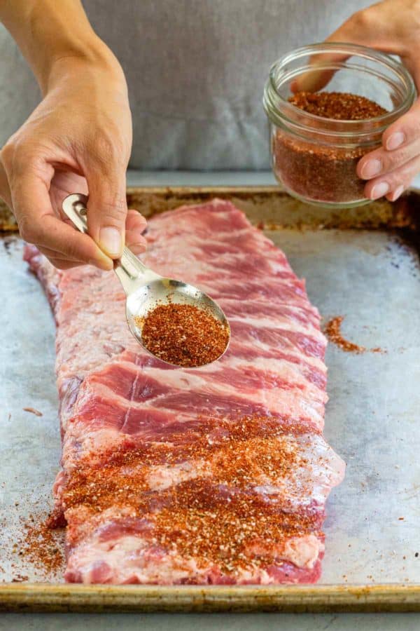 sprinkle spices over a rack of ribs