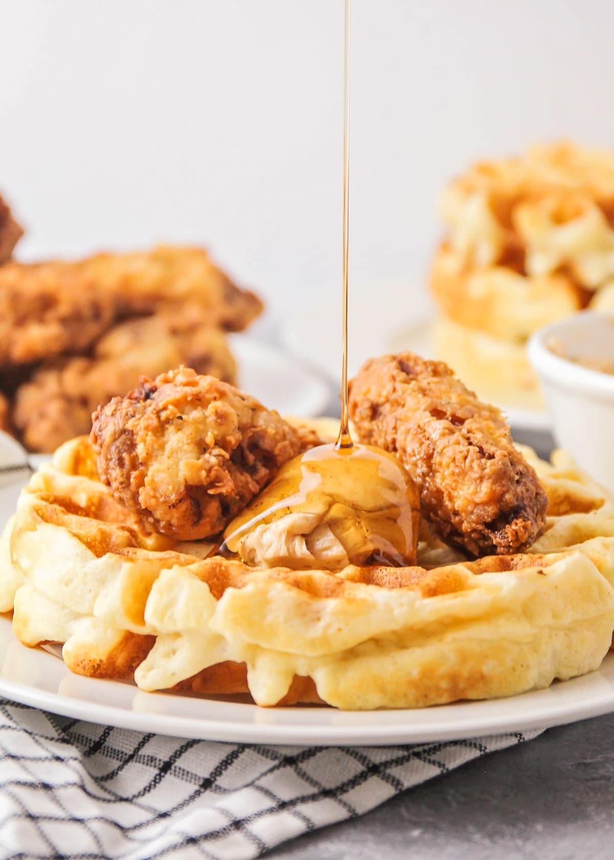 Syrup drizzled on a plate of chicken and waffles.