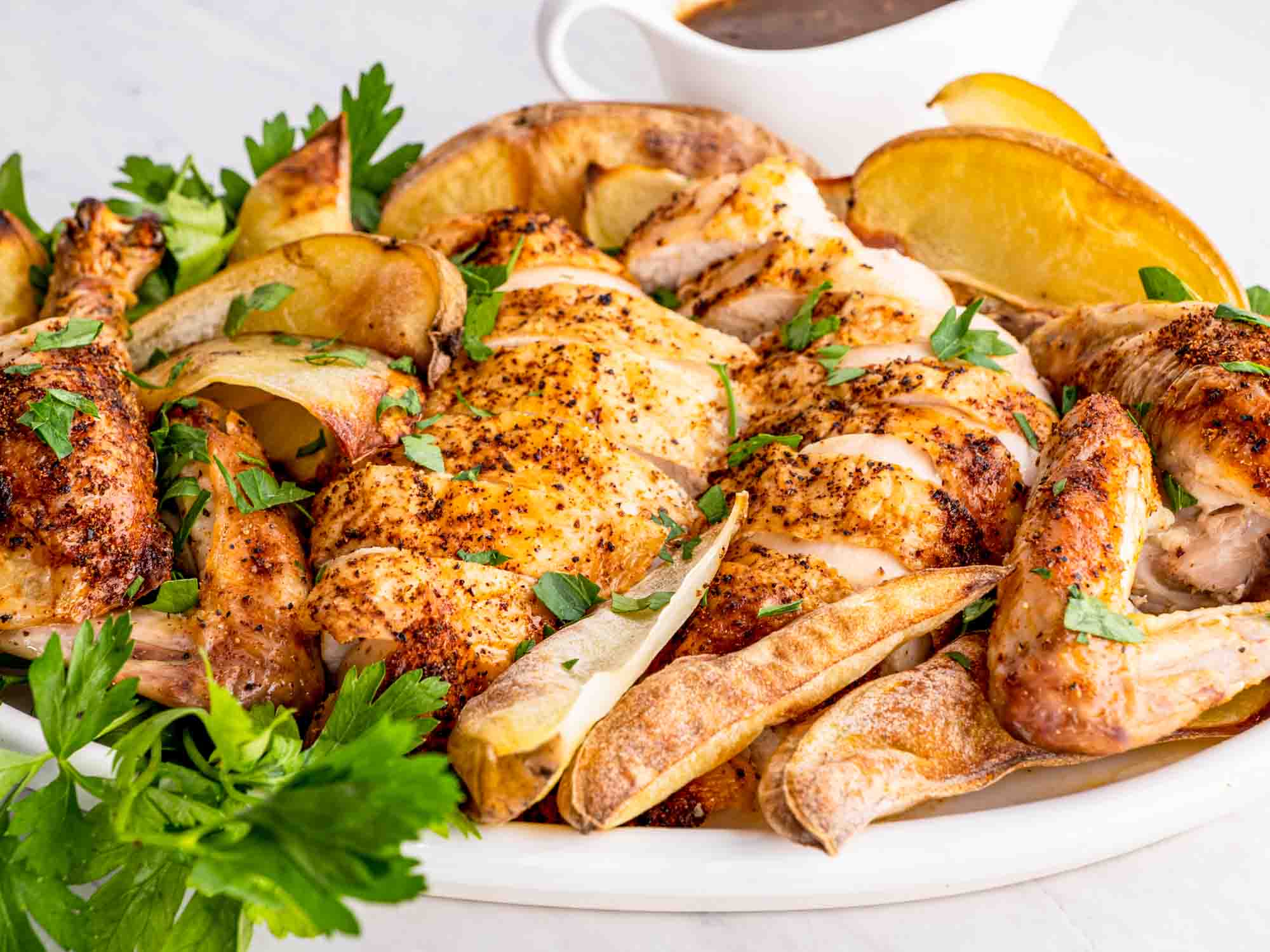 a roast chicken carved up on a platter with some roasted potatoes.