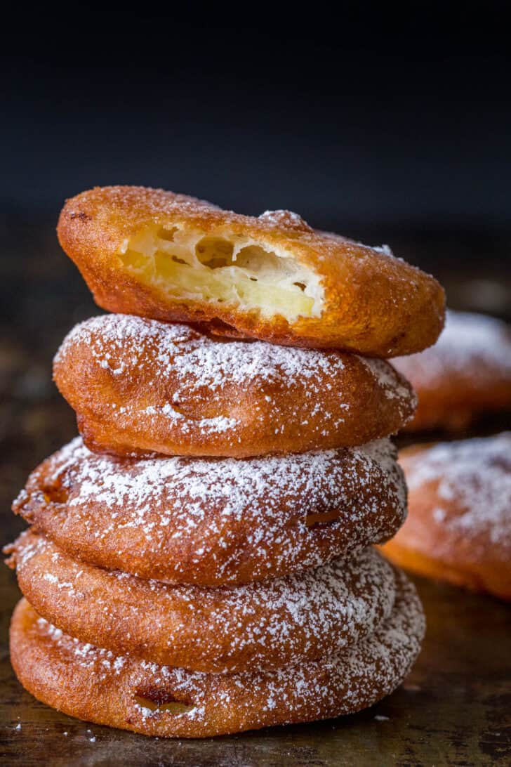 Stack of apple fritter rings dusted with powdered sugar