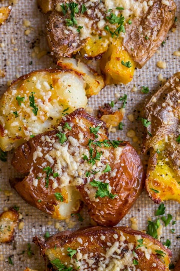 These cheesy smashed potatoes served on a baking sheet with cheese and parsley