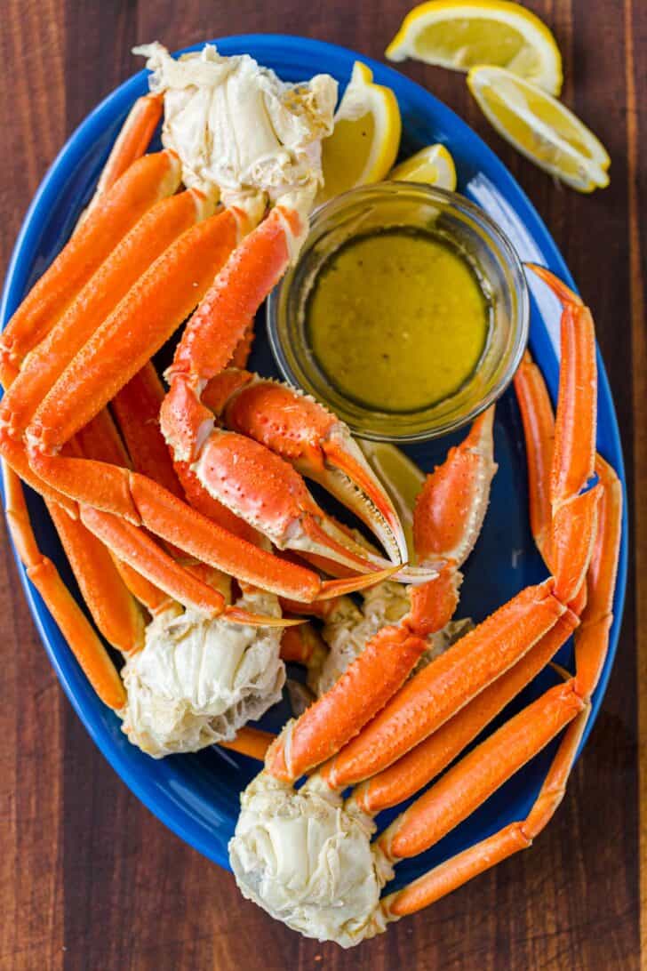 Cooked crab legs on blue platter served with dipping sauce
