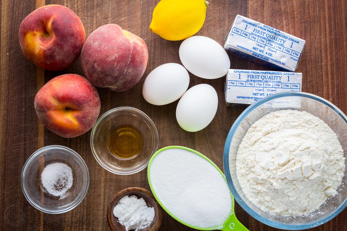 Ingredients for making peach cake butter, sugar, lemon zest, vanilla, peaches, eggs, salt, flour, baking powder