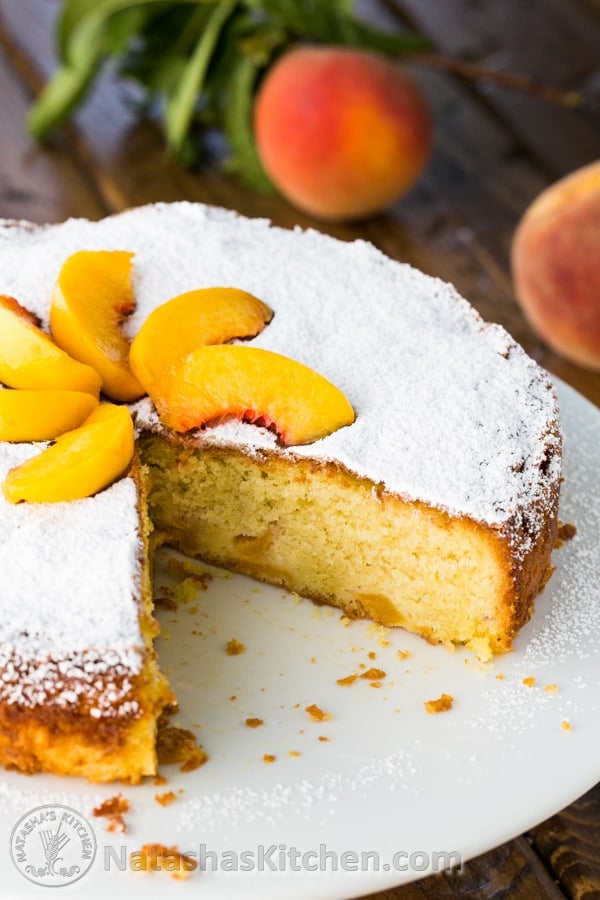 Easy Summer Peach Cake sliced with powdered sugar and fresh peach slices on top