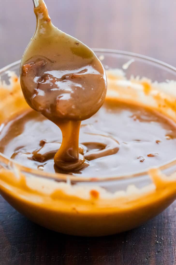 Bacon Caramel Sauce pouring from a spoon into a bowl
