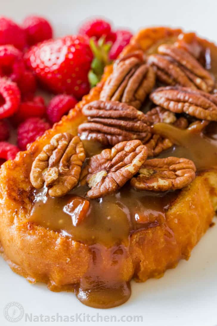 Assembled slice of French toast topped with caramel and pecans