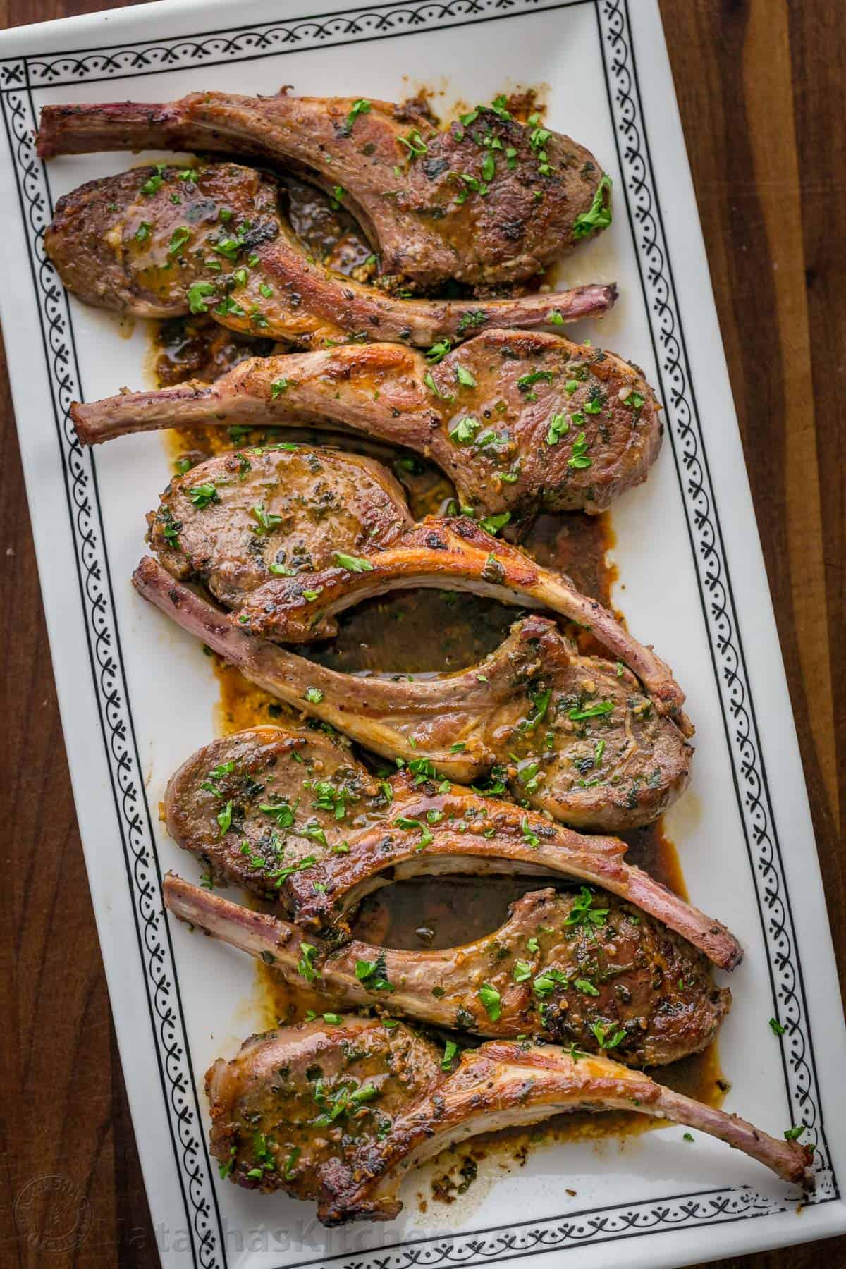 Pan seared lamb chops arranged on a platter served with pan sauce