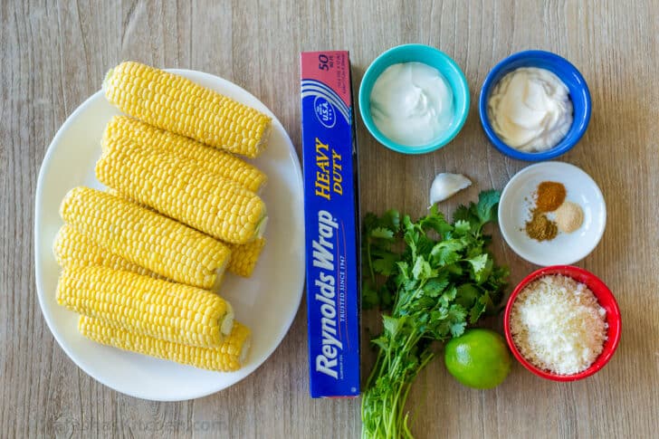 elote ingredients with corn, sour cream, mayo, cotija cheese, lime, cilantro, garlic, and spices