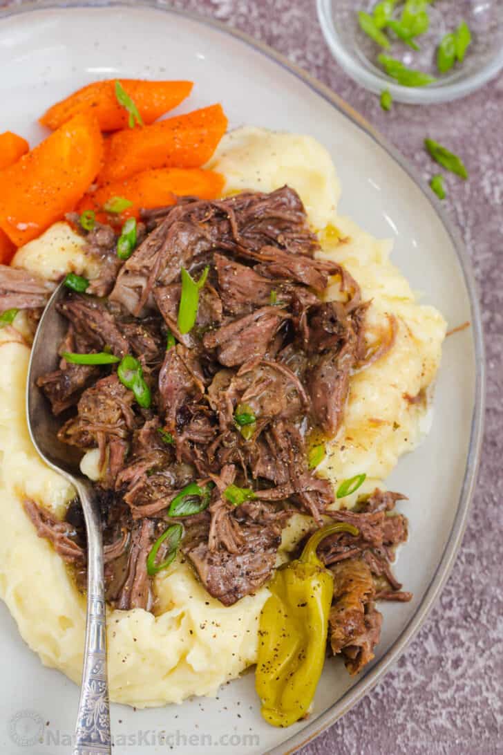 Mississippi roast over mashed potatoes with a spoon.
