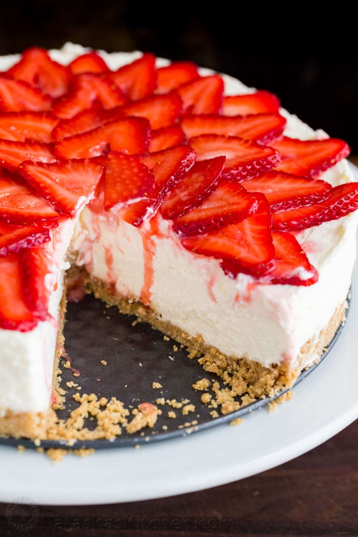 Sliced no bake cheesecake on a serving platter with strawberry topping