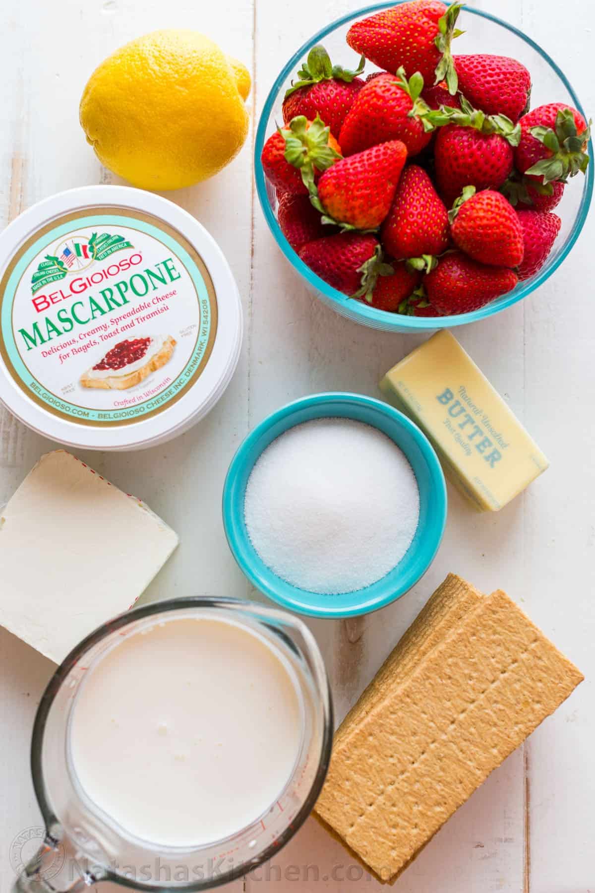 ingredients for no bake cheesecake with strawberries, mascarpone, cream cheese, lemon juice, graham crackers and whipping cream