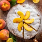 Fresh peach cake dusted with powdered sugar and topped with fresh peach slices