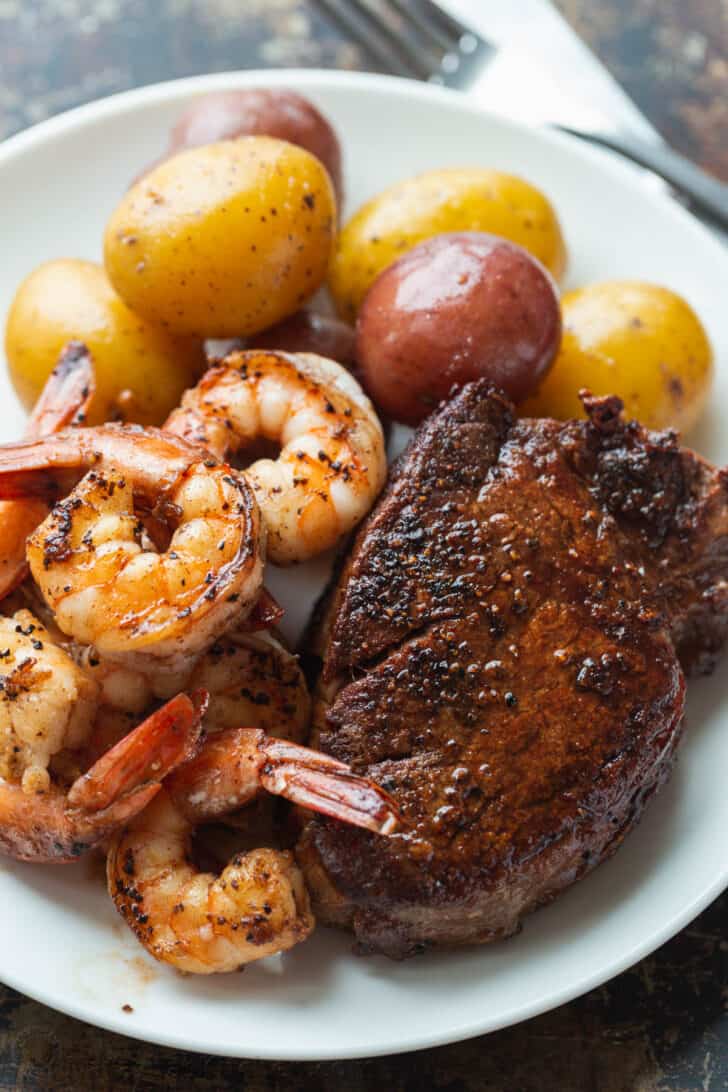Plated steak and shrimp served with new potatoes