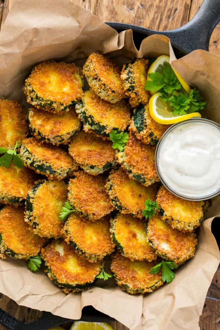 Skillet filled with fried zucchini crisps and dipping sauce