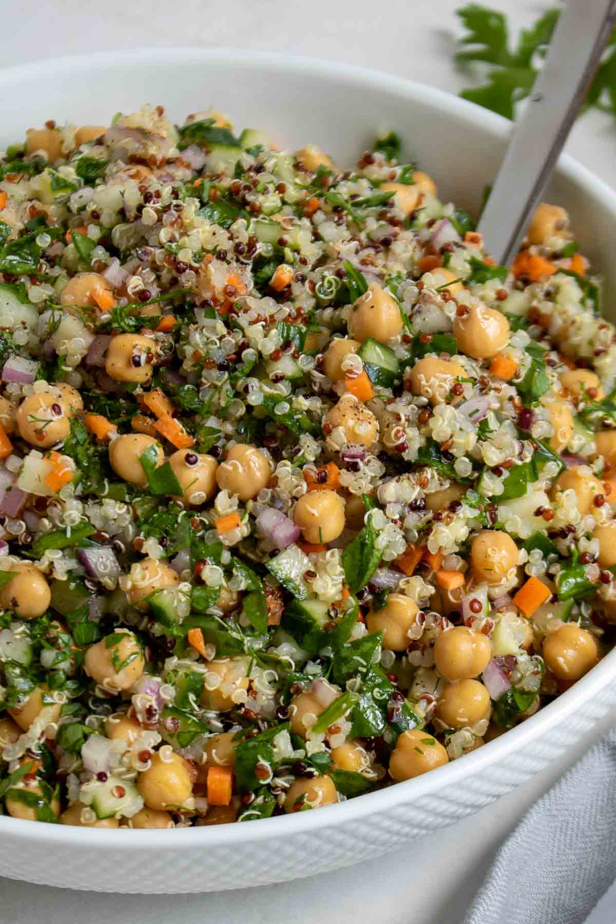Close up of chickpea quinoa salad in a serving dish with a spoon.