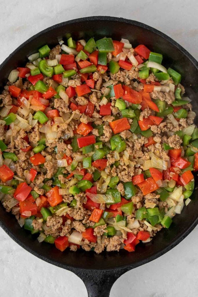 Cooked ground sausage with onion and bell peppers in a pan
