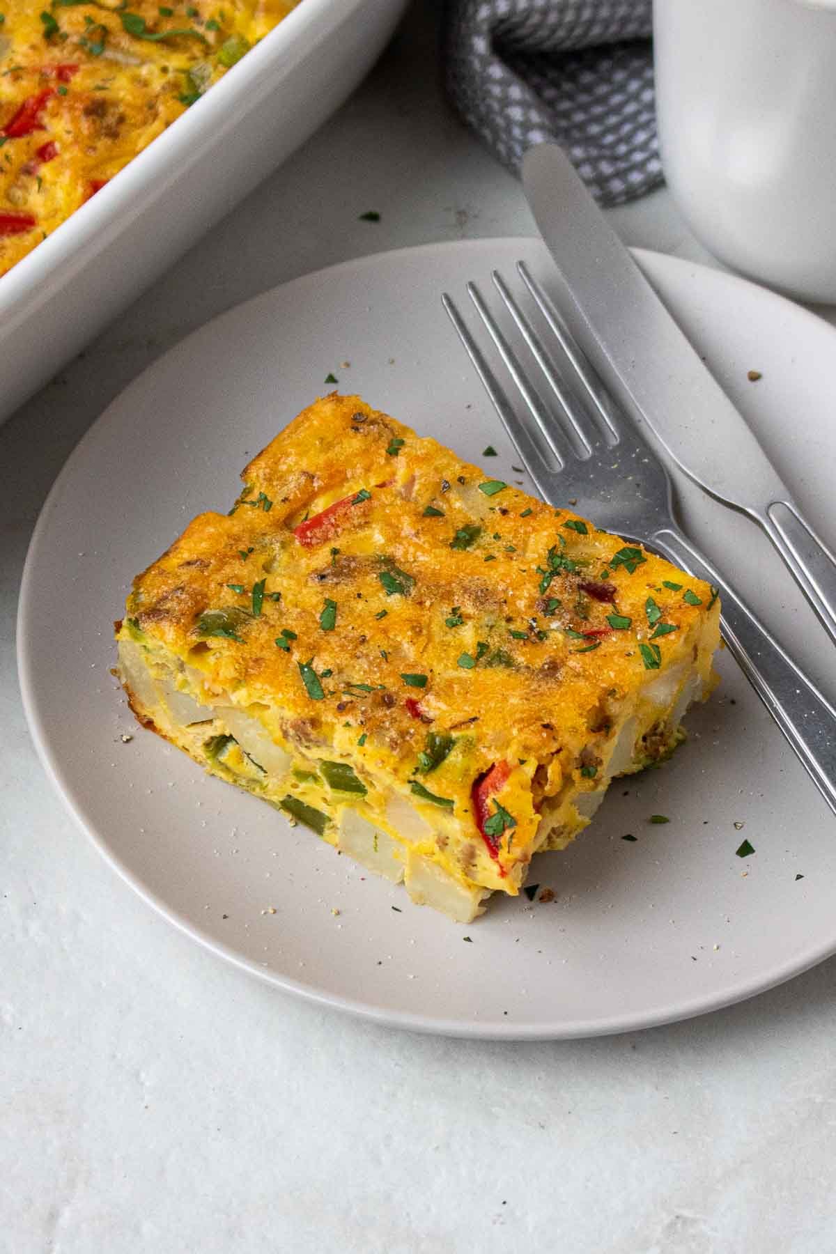 Slice of breakfast casserole with potatoes with sausage and bell peppers on a plate