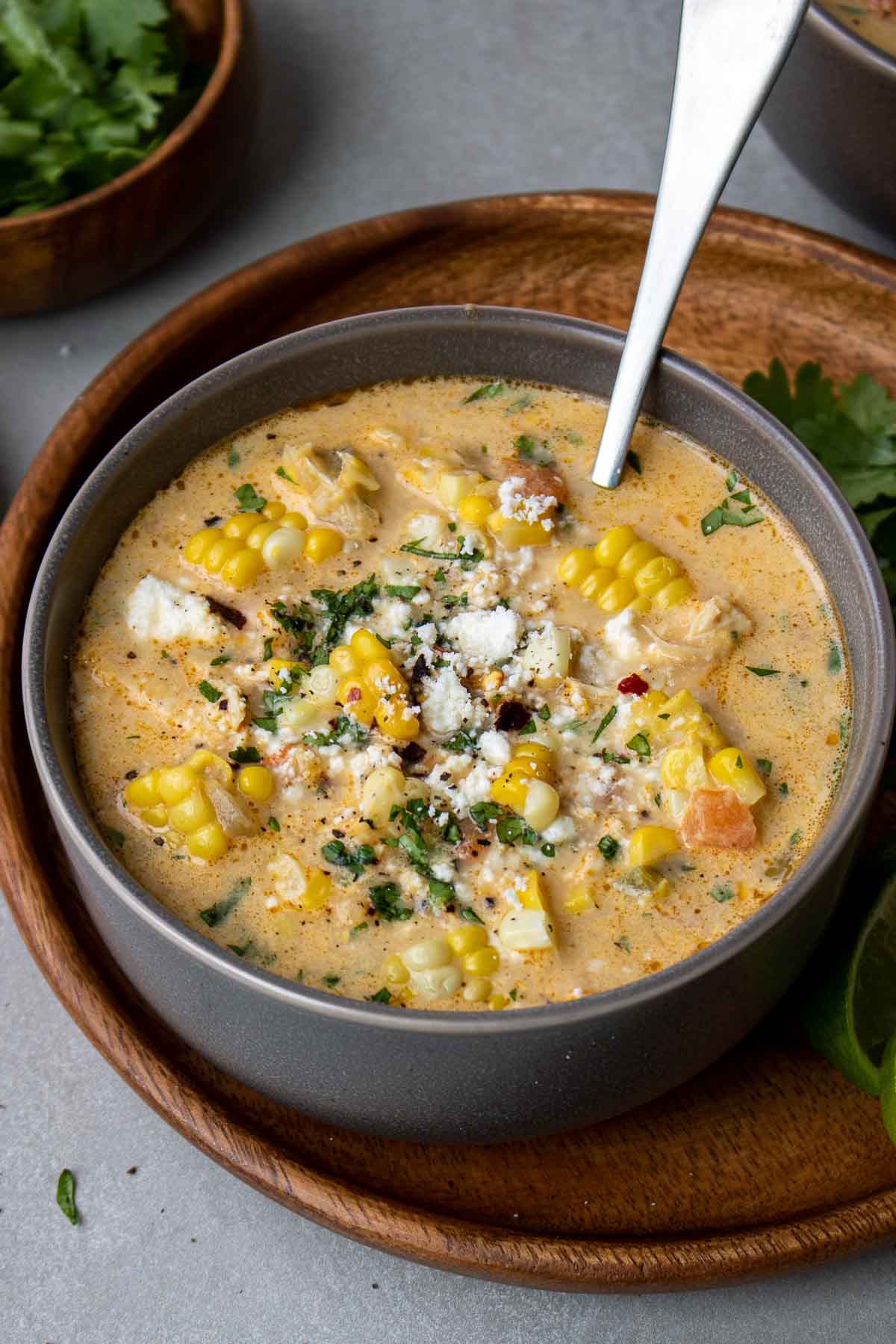 Sweet corn chicken soup in a bowl with cilantro, chilies, and Mexican cheese on top. 