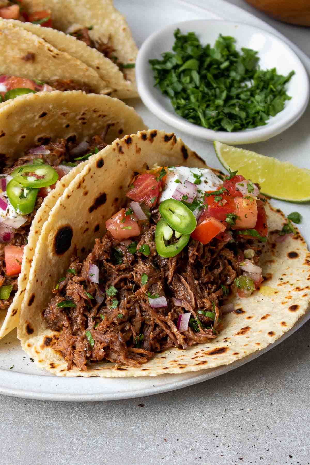 Close up of a shredded beef taco on a plate with toppings.