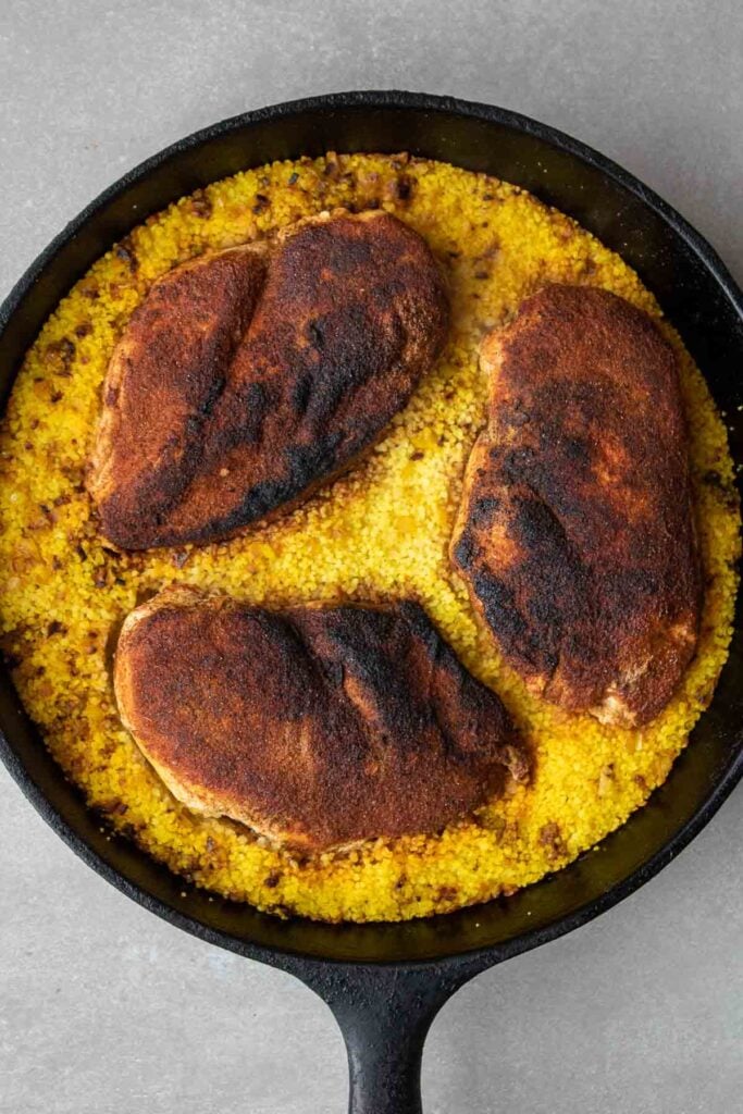 Couscous and chicken breasts with Moroccan spices in cast iron skillet