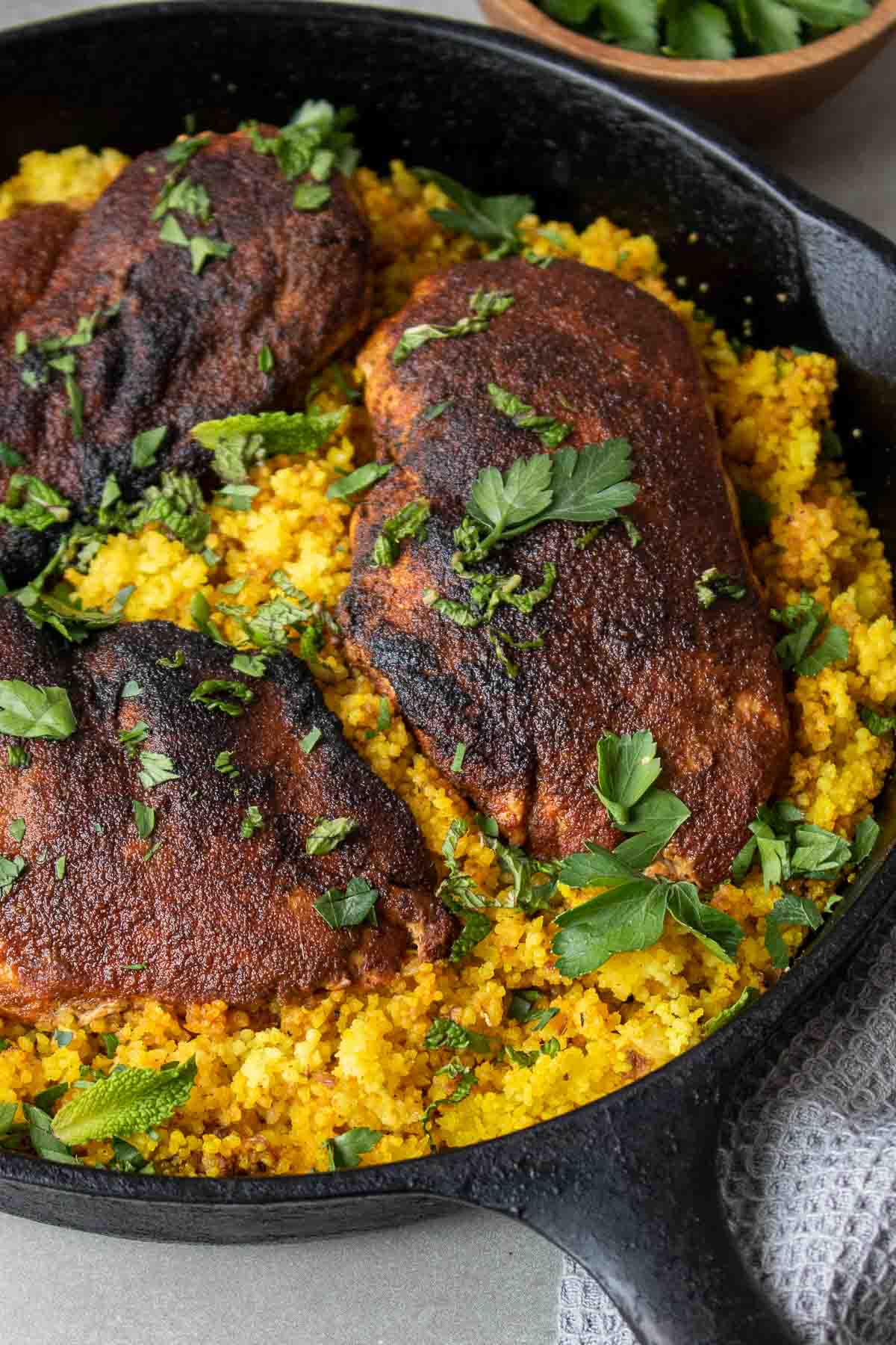 Vue rapprochée de poulet cuit avec des épices marocaines et du couscous dans une poêle en fonte avec de la menthe fraîche et de la coriandre