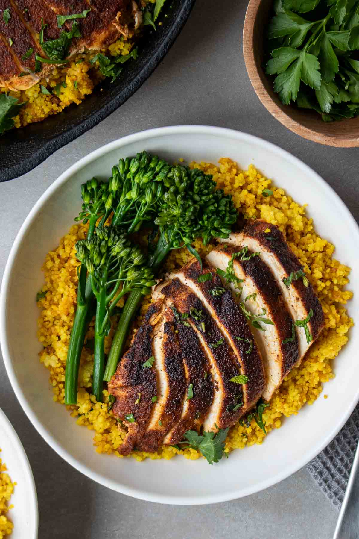 Bowl of golden couscous with sliced chicken with Moroccan spices and broccolini