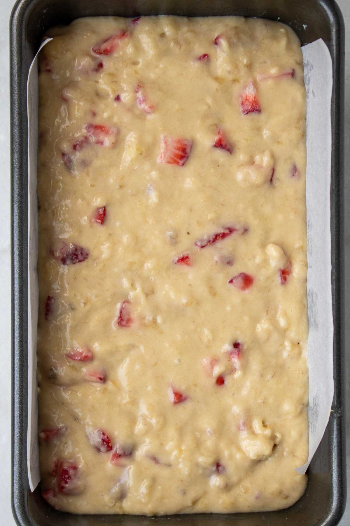 Image of strawberry banana bread in a loaf baking pan.