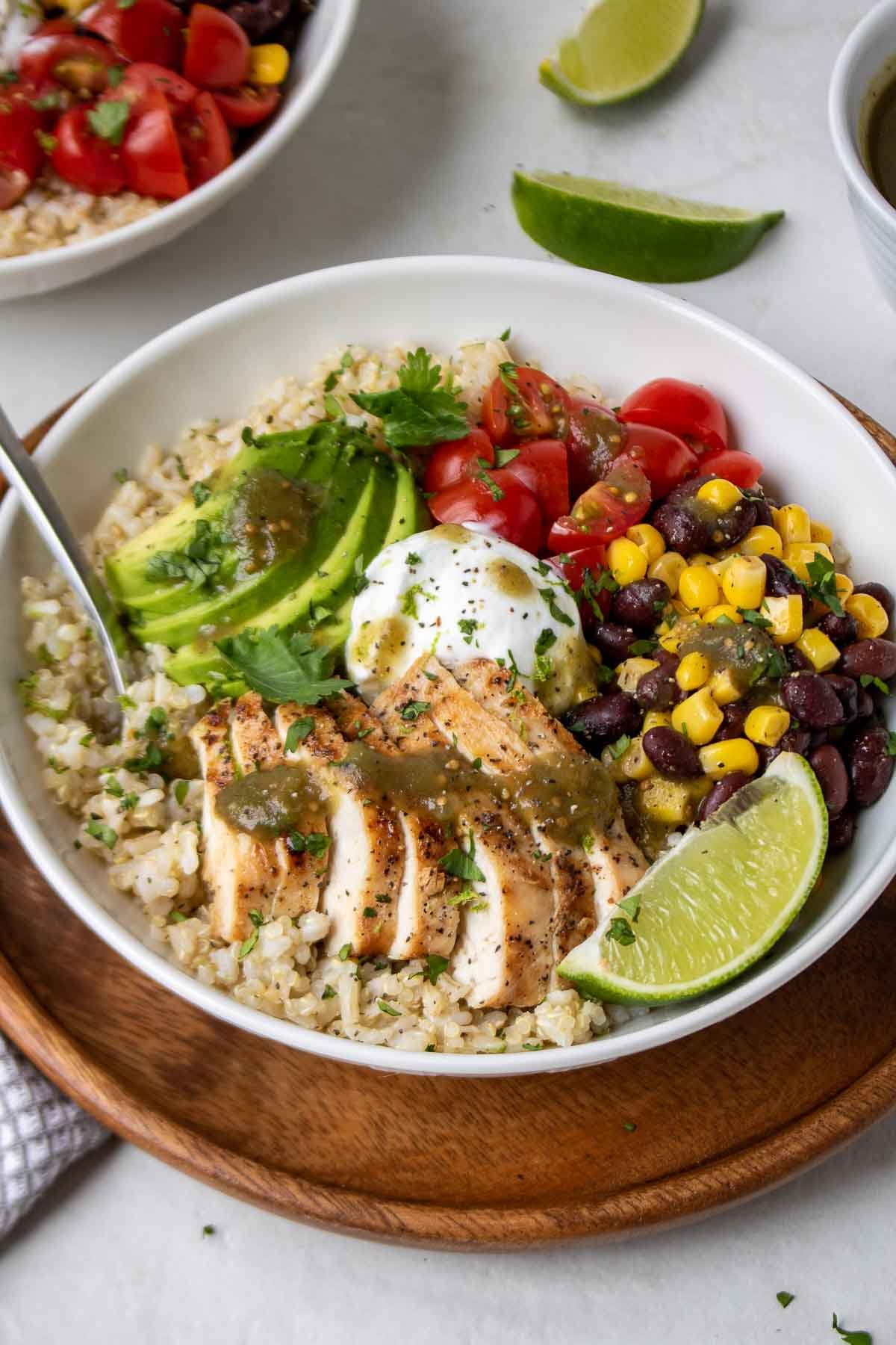 Overhead view of two chicken Baja grain bowls with lime wedges on the side.