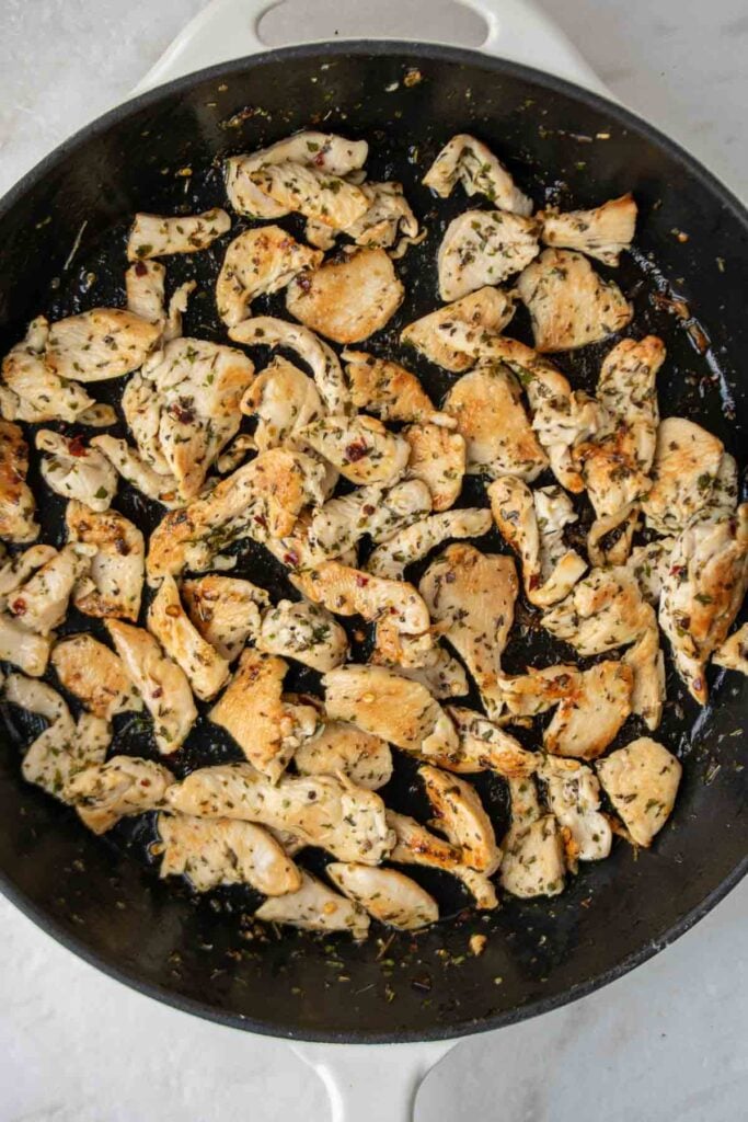 Cooked chicken with herbs in a cast iron skillet.