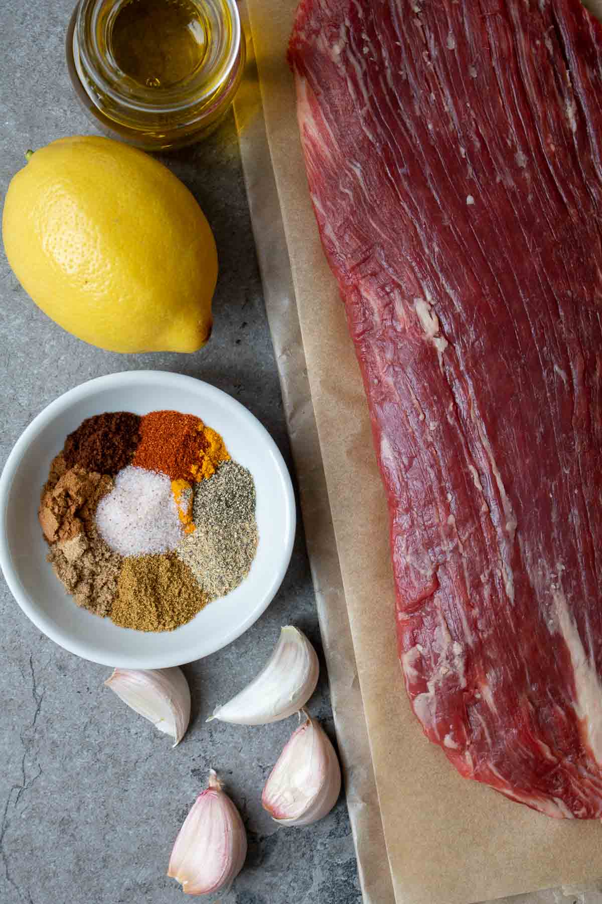Ingredients for beef shawarma; flank steak, olive oil, lemon juice, garlic, and shawarma spices.