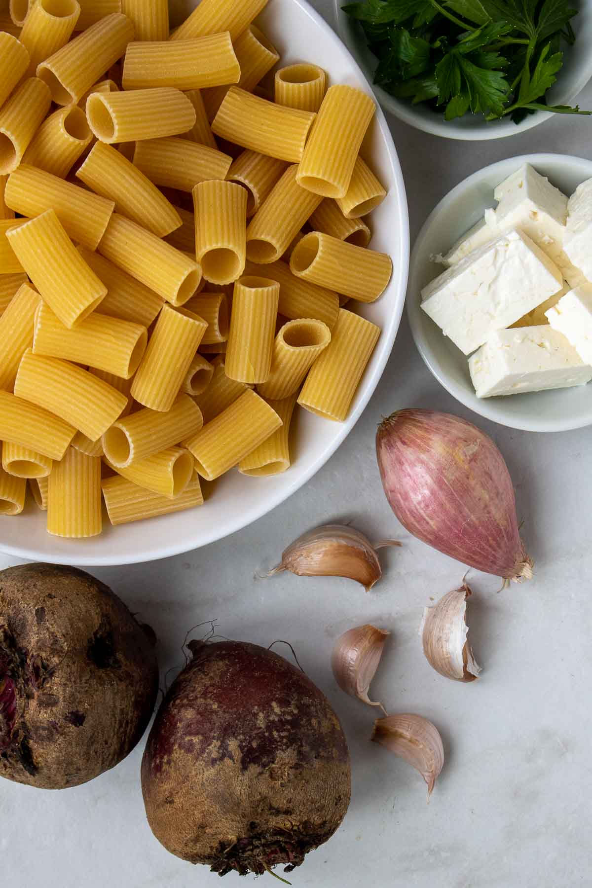 Ingrédients pour les pâtes aux betteraves ; rigatoni, betteraves rouges, échalote, ail, feta et persil.